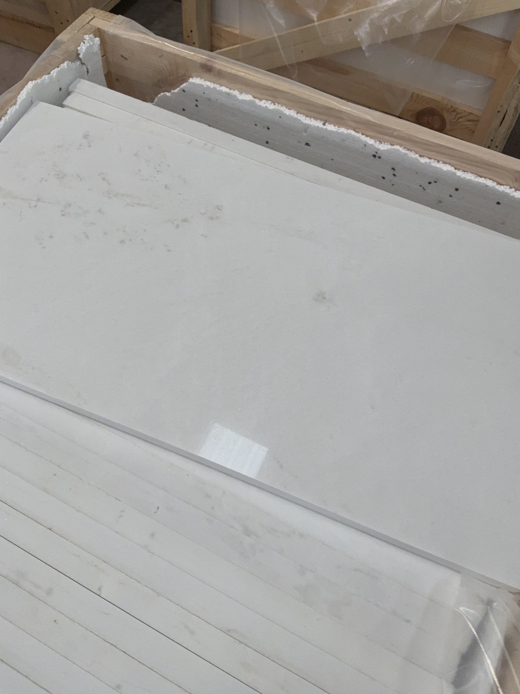 Top view of marble slabs packed in a timber crate showing their cut edges and natural veining