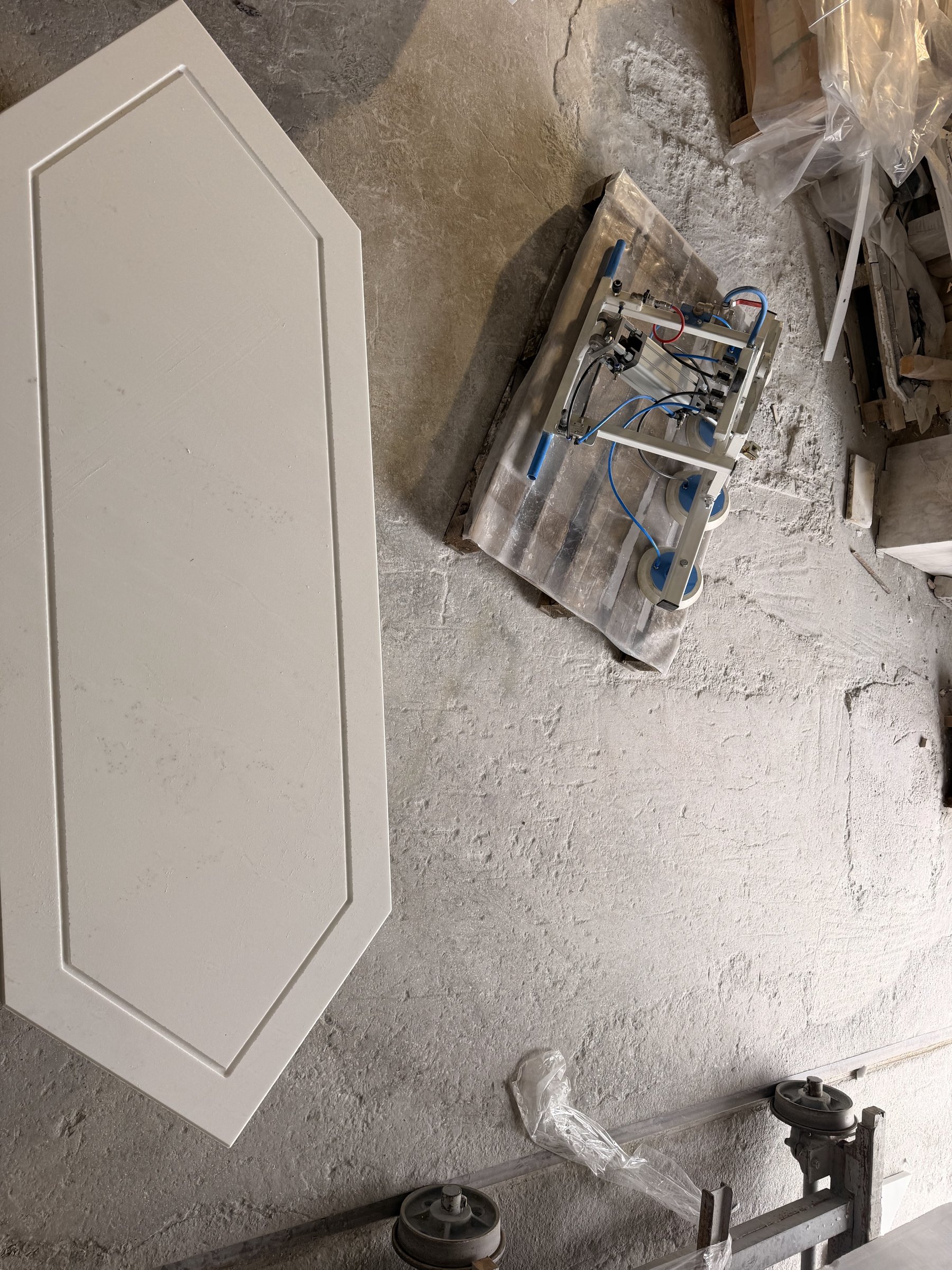 Cut hexagonal white marble panel with a raised border being finished in the workshop
