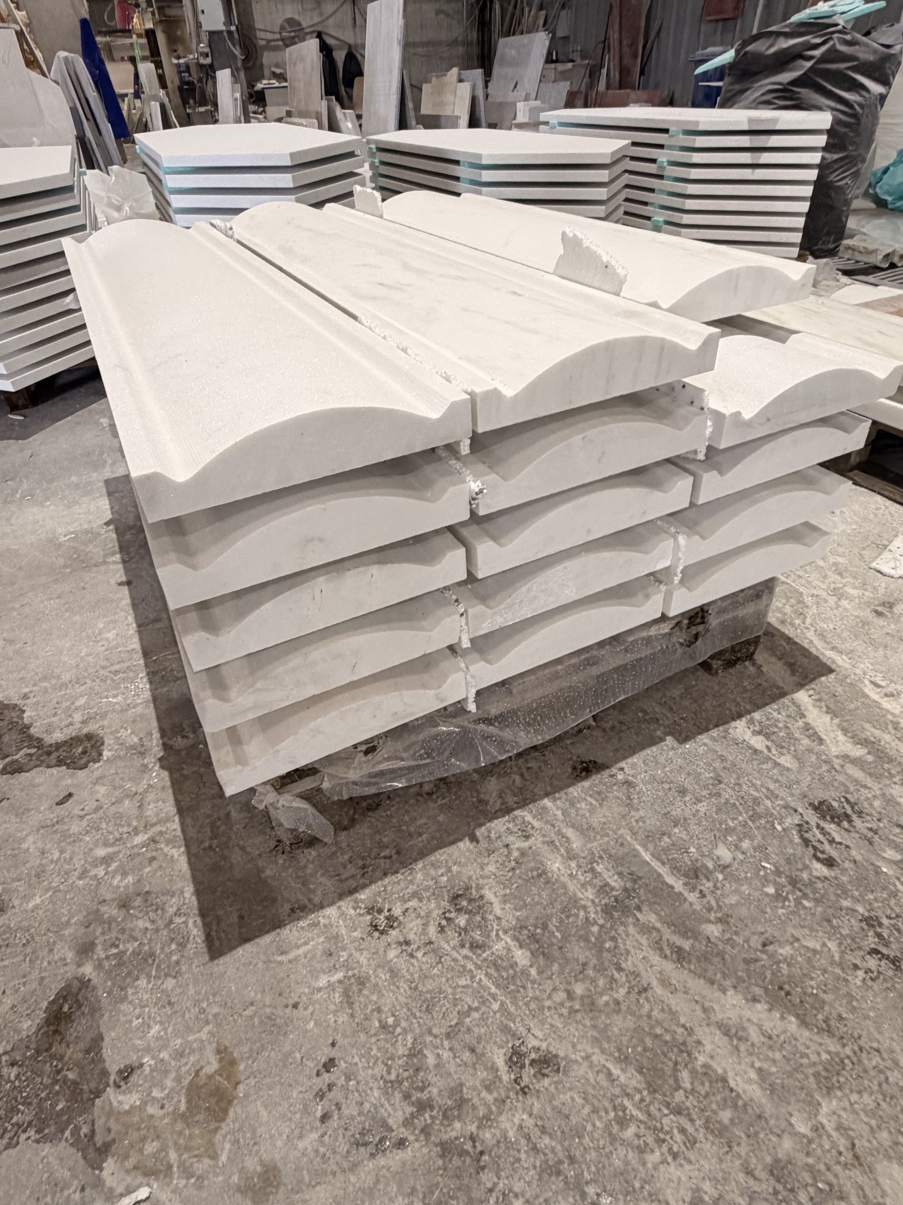 Stack of curved white marble cornice mouldings ready for packing