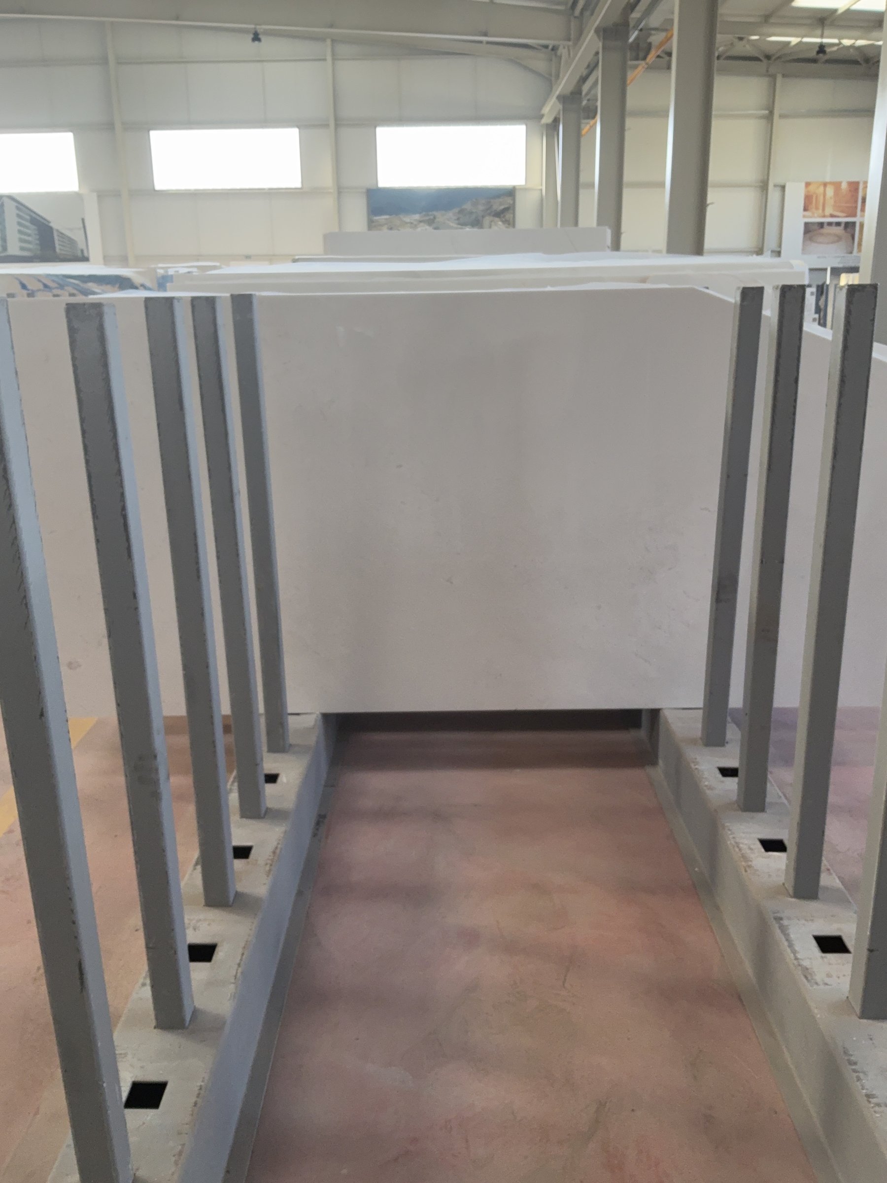 Polished marble slab standing on a steel rack inside a stone processing hall