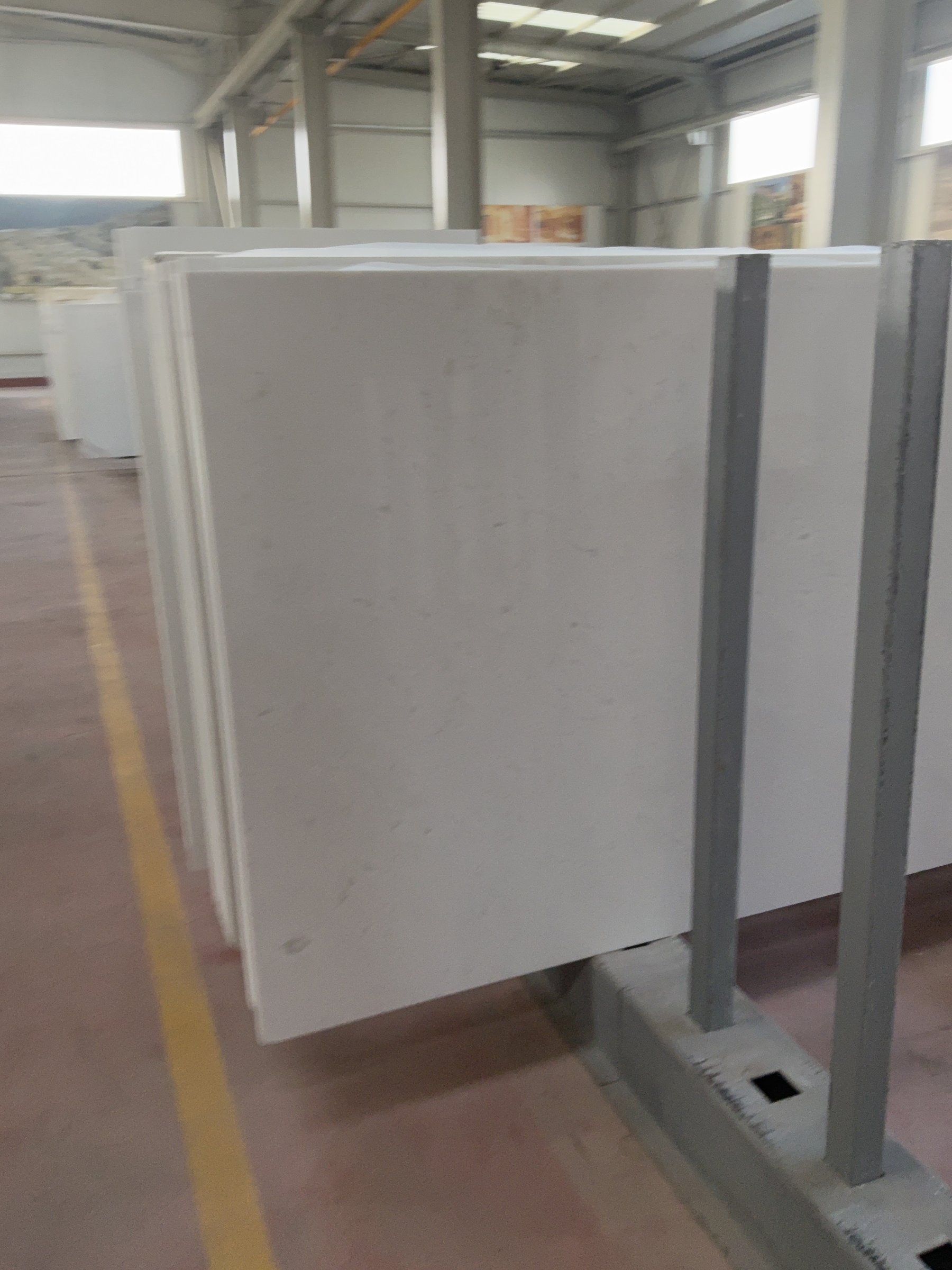 Polished white marble slab with light grey veins resting on a steel storage rack