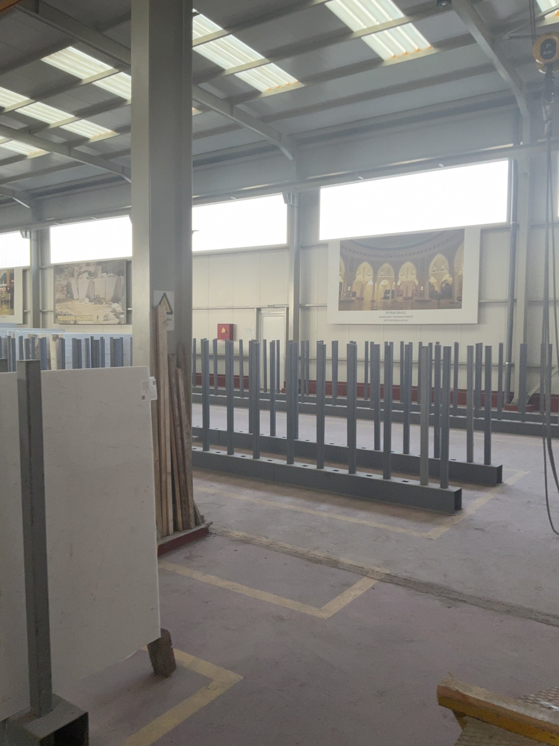 Wide view of a stone warehouse with rows of marble slabs on racks